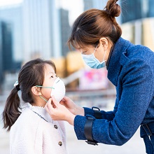 Asian woman and her daughter wearing masks in city street